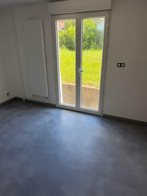 Pièce de vie terminée — sol en béton ciré gris, baie vitrée