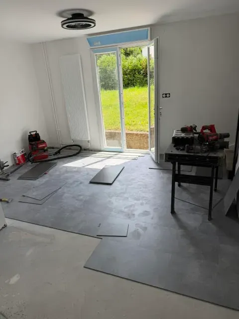 Pièce de vie en chantier, sol brut, baie vitrée