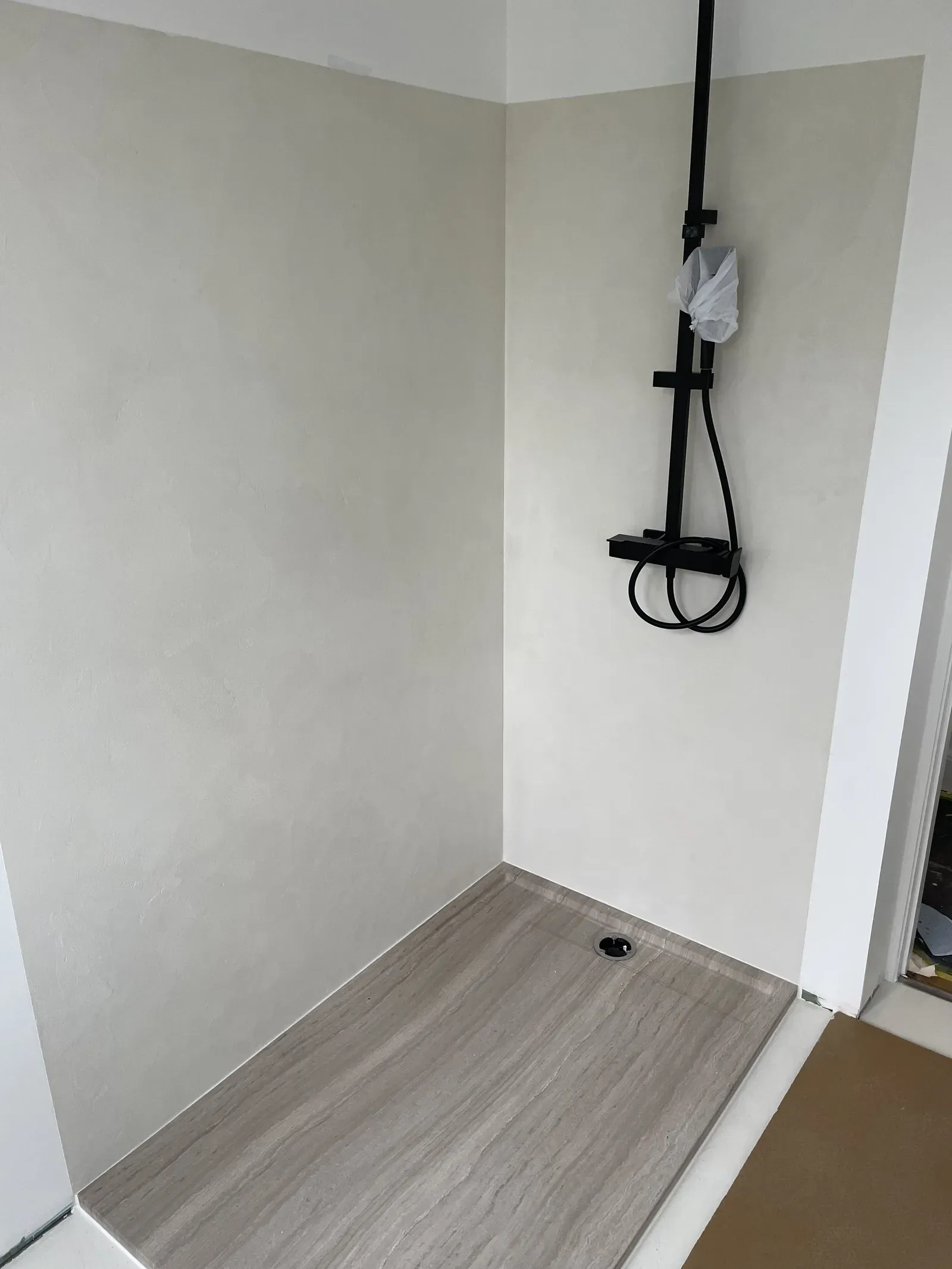 Douche en béton ciré aux murs avec colonne de douche noire